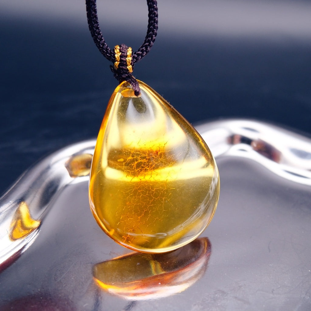 Pendant: transparent golden-yellow Baltic amber teardrop with a crackle-pattern inclusion, dark cord, hanging
