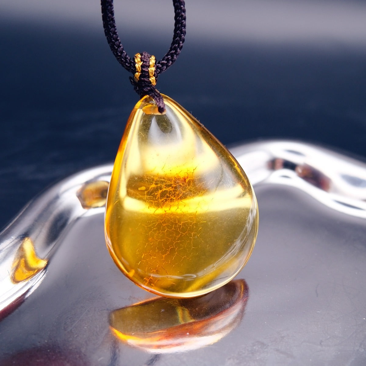 Pendant: transparent golden-yellow Baltic amber teardrop with a crackle-pattern inclusion, dark cord, hanging