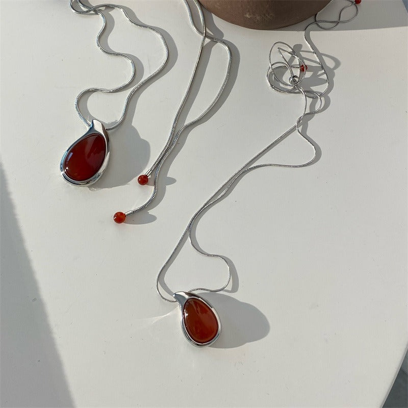 Two pendant necklaces: deep red carnelian teardrops in silver-tone frames on silver snake chains