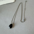 Pendant necklace: black agate teardrop in a silver-tone frame on a silver-tone chain