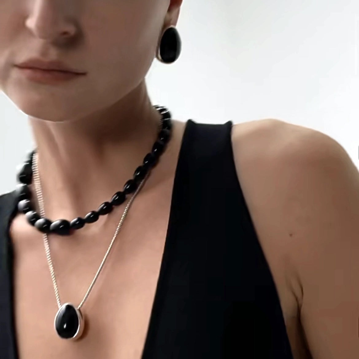 Pendant necklace: black agate teardrop in a silver-tone frame on a chain, fourth view