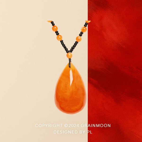Pendant necklace: orange amber teardrop on a strand of small black and orange beads