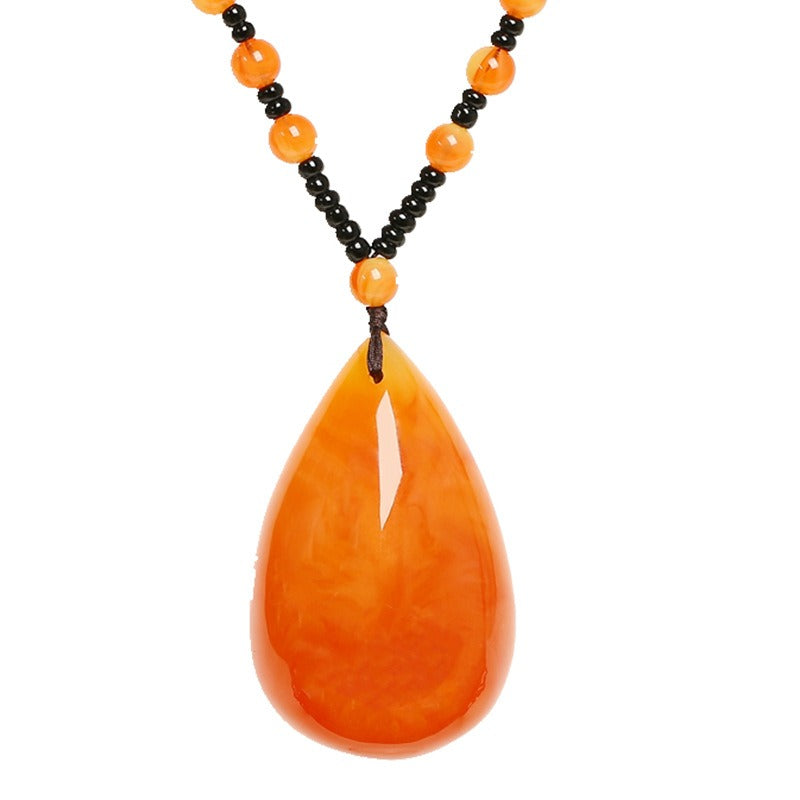 Pendant necklace: orange Baltic amber teardrop on a strand of small beads, second view