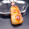 Pendant: Baltic amber carved as a gourd, cream to orange-brown, with a pink bead on a dark cord