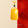 Pendant: opaque yellow amber rectangular plaque with a green bead and yellow beads above it