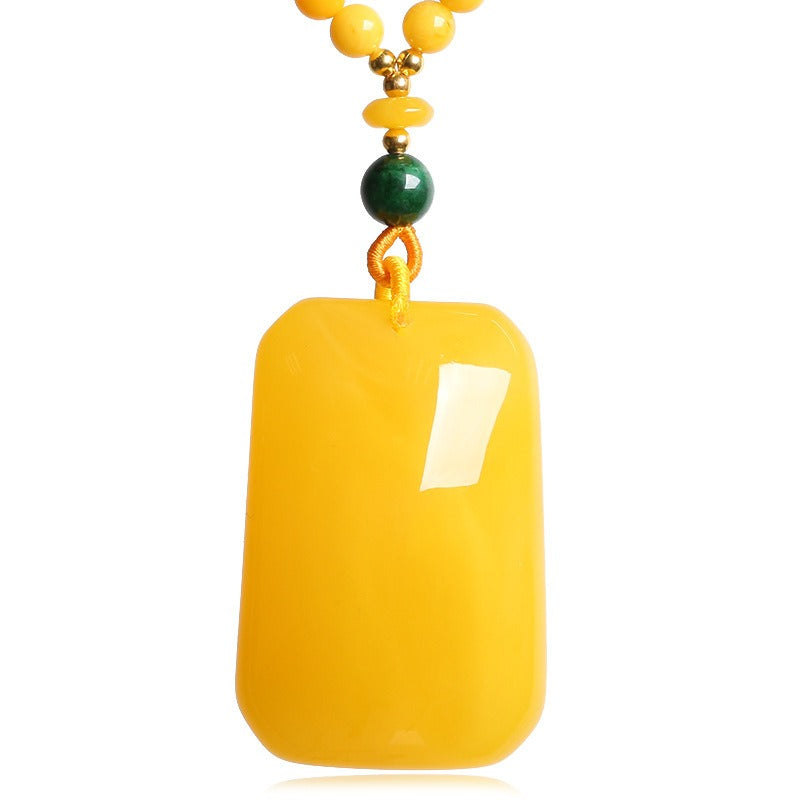 Pendant: opaque yellow amber rectangular plaque with a green bead above it, second view