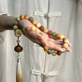 Prayer beads: multi-coloured carved lotus bodhi seed beads draped over an open hand, with a tassel